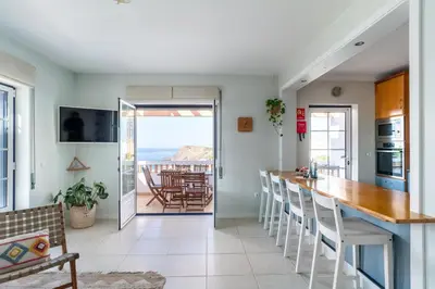 a kitchen and dining room with a view of the ocean at Aloha Apartment Arrifana in Praia da Arrifana