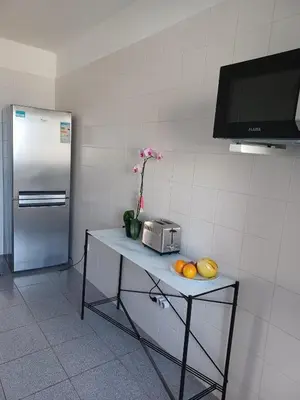 a table with fruit on it in a kitchen with a refrigerator at Apartamento Oliveira in Funchal