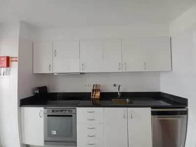 a kitchen with white cabinets and a black counter top at Apartamento Oliveira in Funchal
