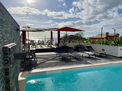 a swimming pool with chairs and umbrellas on a patio at Casa MaBu by Your Madeira Rentals in Paul do Mar