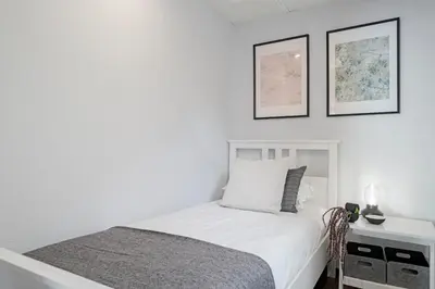 a white bedroom with a bed and two pictures on the wall at Garajau I by An Island Apart in Caniço