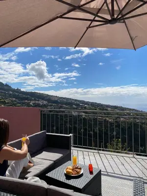 a woman sitting on a couch on a balcony with an umbrella at Mine House in Calheta