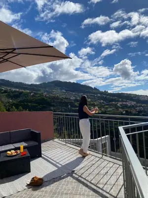 a woman standing on a balcony with an umbrella at Mine House in Calheta