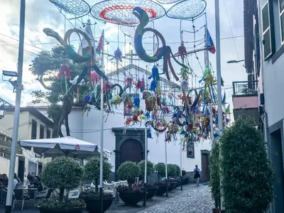 a street with a bunch of decorations hanging from a building at Village Lobos Flat in Câmara de Lobos
