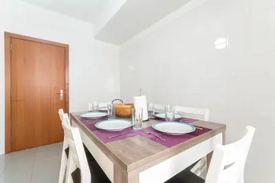 a dining room table with white chairs and a wooden tableablish at Village Lobos Flat in Câmara de Lobos