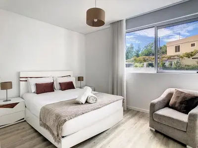 a white bedroom with a bed and a chair at Uptown Apartment by LovelyStay in Funchal