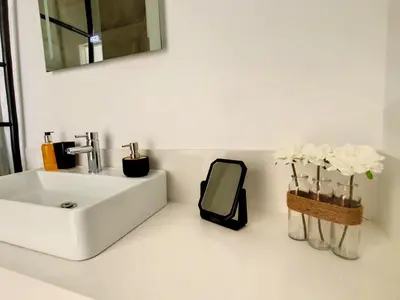 a bathroom with a sink and a mirror and flowers at Uptown Apartment by LovelyStay in Funchal