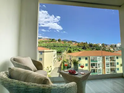 a balcony with two chairs and a table with wine glasses at Uptown Apartment by LovelyStay in Funchal