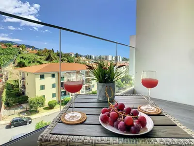 a table with two glasses of wine and a plate of fruit at Uptown Apartment by LovelyStay in Funchal