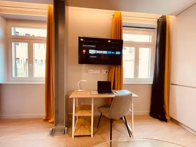 a room with a table with a laptop and a television at Living Funchal Executive in Funchal