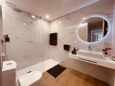 a white bathroom with a sink and a mirror at Living Funchal Executive in Funchal