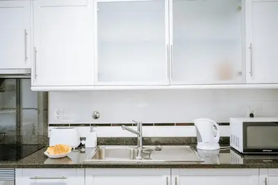 a kitchen with white cabinets and a sink at Apartamento Feliz by Amazing Madeira in Funchal
