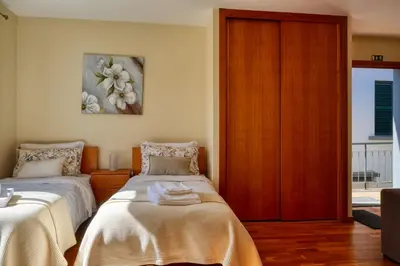 a bedroom with two beds and a wooden cabinet at Largo dos Milagres, a Home in Madeira in Machico