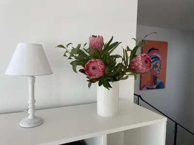 a white vase with pink flowers on a white table at Villa Sea View in Arco da Calheta