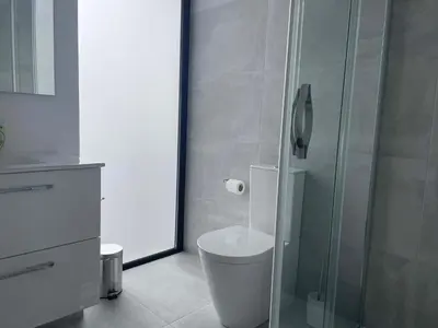a bathroom with a toilet and a glass shower at Villa Sea View in Arco da Calheta