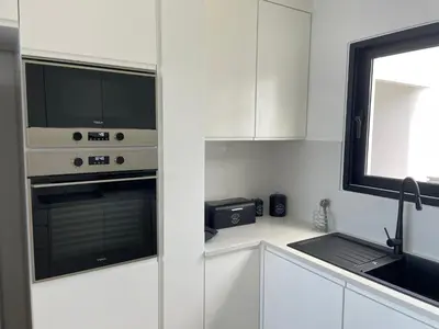 a kitchen with white cabinets and a sink and a microwave at Villa Sea View in Arco da Calheta