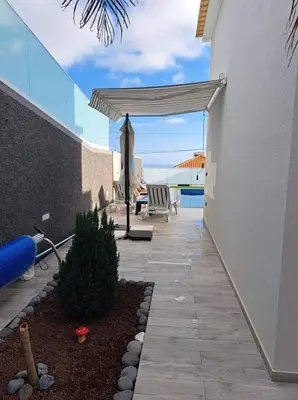 a patio with awning and a table and a bench at Vila Castro in Estreito da Calheta