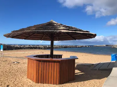 an umbrella sitting on a beach with the ocean at Vila Castro in Estreito da Calheta