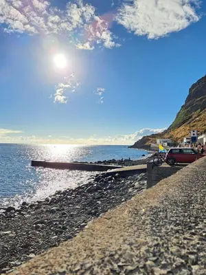 a car parked on a beach next to the water at Vila Castro in Estreito da Calheta