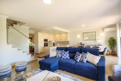 a living room with a blue couch and a kitchen at Casa da Boa Vida at Boa Vista Golf Resort Bayview in Lagos