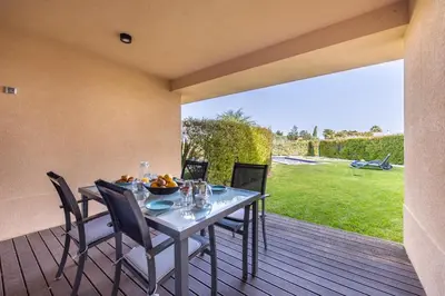 a dining table and chairs on a wooden deck at CoolHouses Algarve, Luz 2 bed elegant flat, private pool & garden, SPA facilities, Mar da Luz 19 in Luz