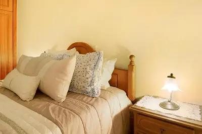 a bedroom with a bed with pillows and a lamp at Palheiro Residence Familiar 2 in Funchal