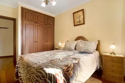 a bedroom with a bed and a dresser with two lamps at Palheiro Residence Familiar 1 in Funchal
