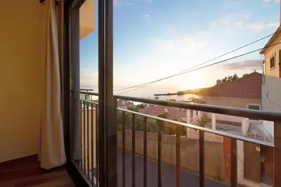 a room with a balcony with a view of the ocean at Palheiro Residence Familiar 1 in Funchal