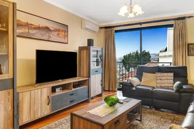 a room with a couch and a large window at Palheiro Residence Vista Mar in Funchal