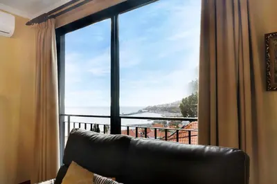 a black leather couch with pillows next to a lamp at Palheiro Residence Vista Mar in Funchal