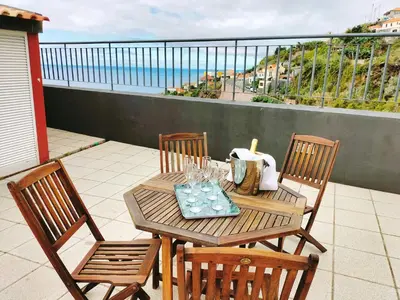 a table and chairs on a balcony with a view of the ocean at Villa Fanny in Ribeira Brava