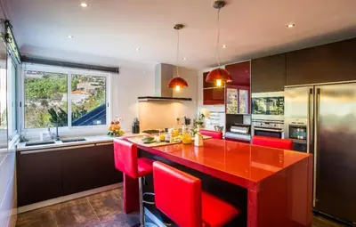 a kitchen with red chairs and a red counter top at Villa Fanny in Ribeira Brava