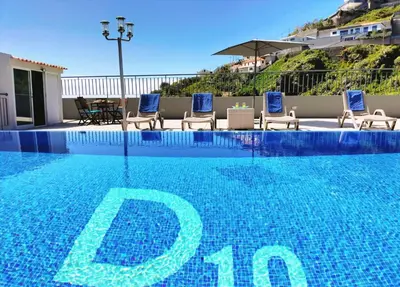 a swimming pool with chairs and a sign on it at Villa Fanny in Ribeira Brava