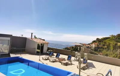 a swimming pool with chairs and a view of the ocean at Villa Fanny in Ribeira Brava