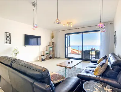 a living room with leather furniture and a view of the ocean at Apartment Nata by Holiday Rental Madeira in Caniço