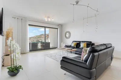 a living room with a black leather couch and a glass table at Apartment Nata by Holiday Rental Madeira in Caniço