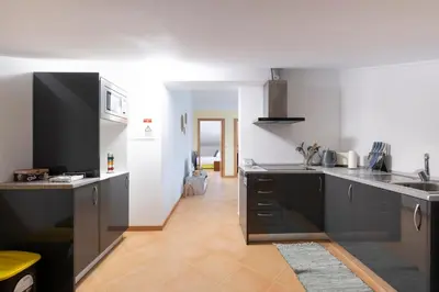 a kitchen with black and white appliances and a hallway at Sara House in Ponta do Sol