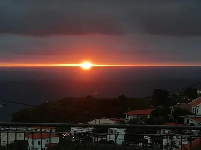 a sunset over the ocean in a city at Sara House in Ponta do Sol