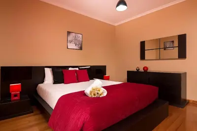 a bedroom with a large bed with a red blanket at KING´S HOUSE (Sea View and Indoor BBQ) in Estreito da Calheta