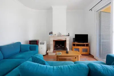 a living room with a blue couch and a fireplace at Casa de férias a 75 metros da praia in Campo de Baixo