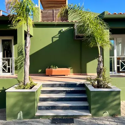a green building with a staircase with palm trees at Country Villa work&relax in Lagos