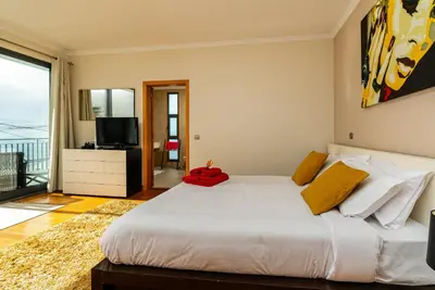 a bedroom with a large white bed and a television at Villa Nunes, Big Holiday house with private pool in Calheta