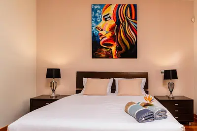 a bedroom with a bed with a painting on the wall at Villa Nunes, Big Holiday house with private pool in Calheta