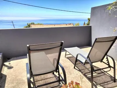 two chairs and a table on a balcony at A Casa Valentina - Estudio vista panorâmica para o mar in Estreito da Calheta