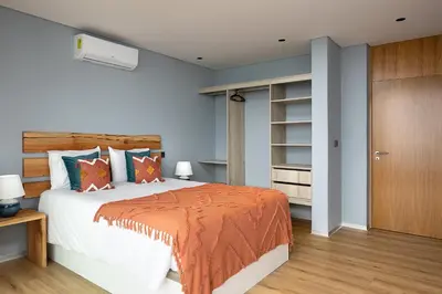a bedroom with a large bed with an orange blanket at King´s Paradise (Heated Pool and Sea View) in Estreito da Calheta