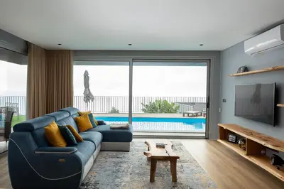 a living room with a blue couch and a tv at King´s View (Heated Pool and Sea View) in Estreito da Calheta