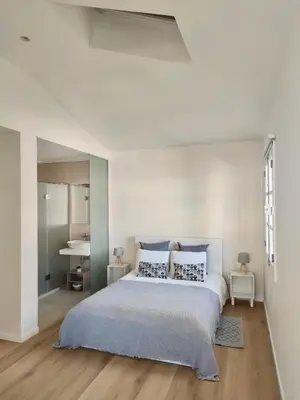 a white bedroom with a large bed with blue pillows at Seven Funchal Apartments in Funchal