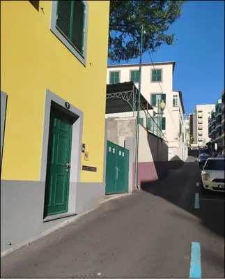 a yellow and green building with green doors on a street at Seven Funchal Apartments in Funchal