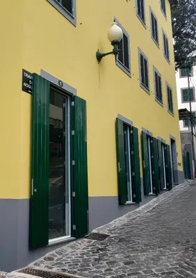 a yellow building with green doors on a street at Seven Funchal Apartments in Funchal