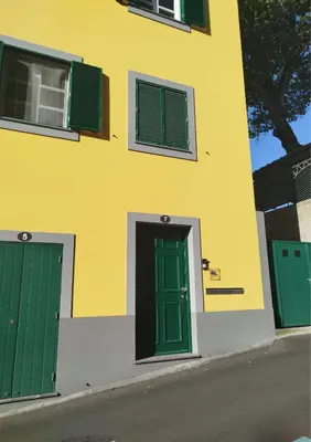 a yellow and green building with two green doors at Seven Funchal Apartments in Funchal